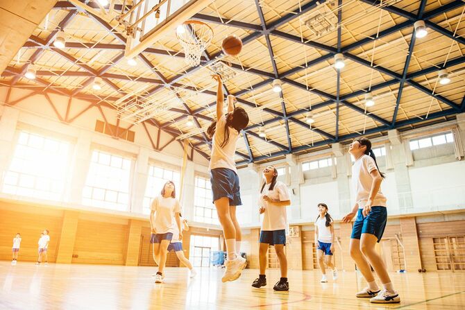 学校のGYMでバスケットボールをしている日本の中学校の女の子の友達。