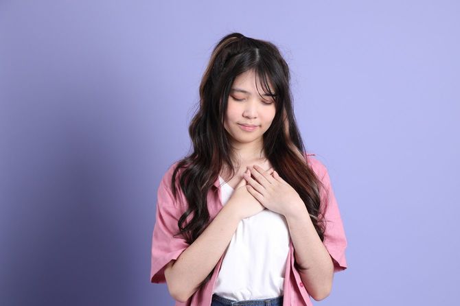 胸に手を当てて目を閉じる女性