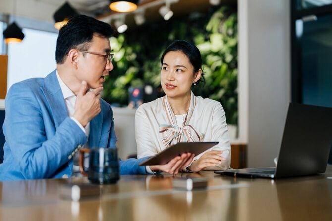 タブレットを手に話し合いをする二人のビジネスパーソン