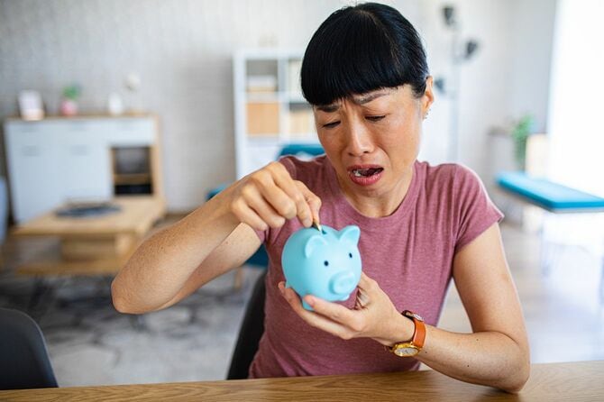 豚の貯金箱を持って困り顔の女性