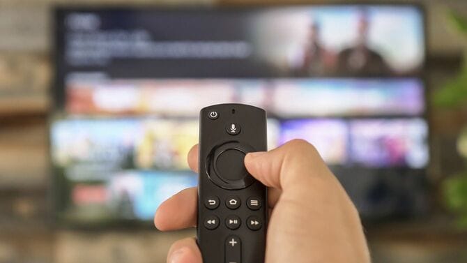 テレビのリモコンを持ち、テレビチャンネルを変更する男性の手