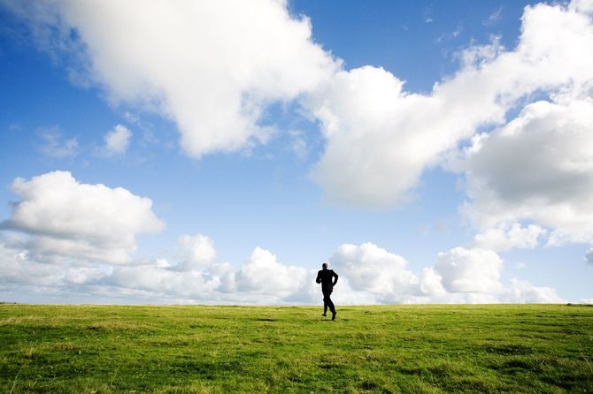 スーツ姿で草原を走っていく男性