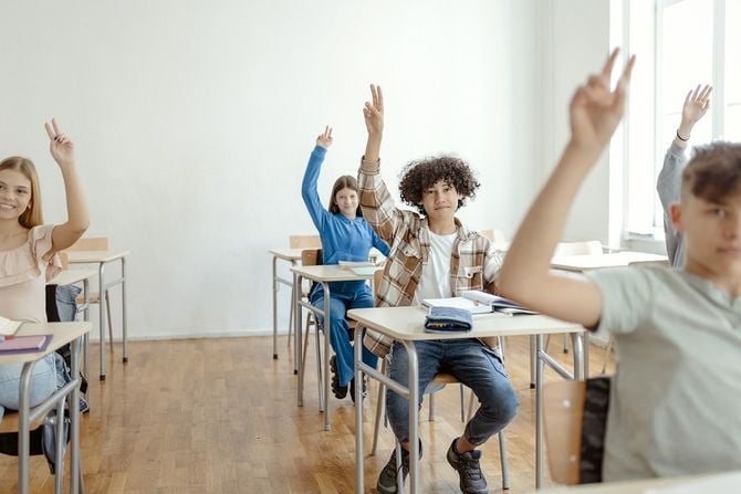 学校の授業で手を挙げる子供たち
