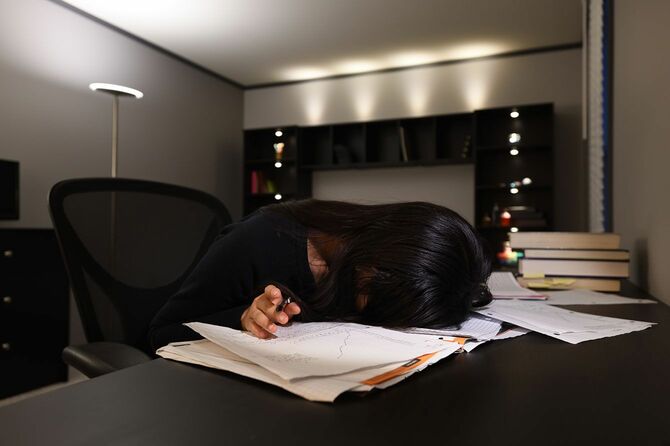 勉強しながら机に突っ伏して寝ている人