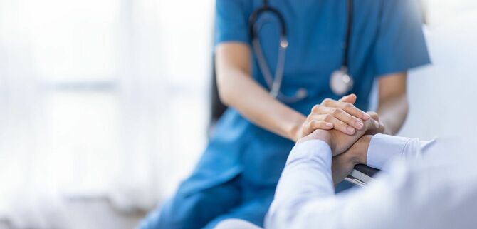 患者の手を握る看護師