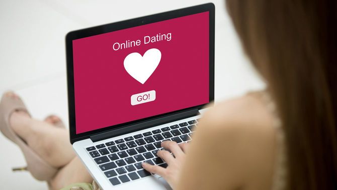ノートパソコンでオンラインの出会い系サイトを閲覧する若く美しい独身女性