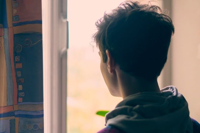 窓の外を眺める悲しい少年