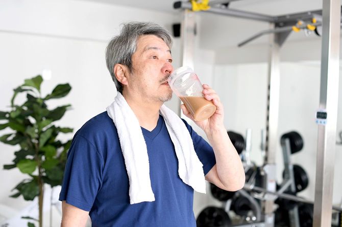 ジムでトレーニングのためにプロテインを飲む男性