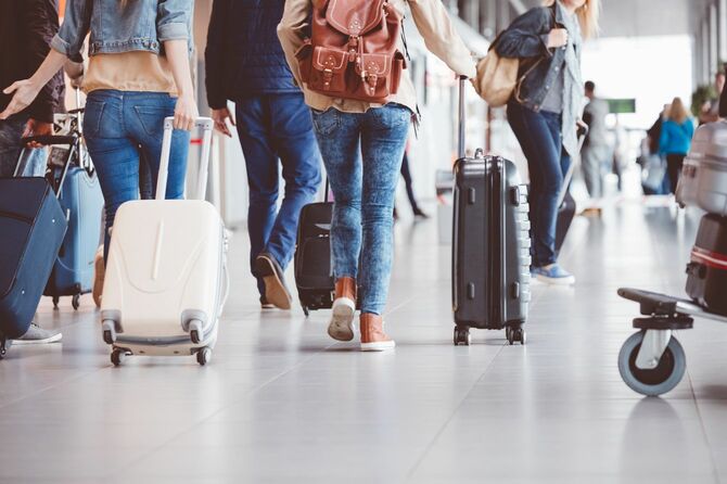 スーツケースを手に空港内を移動する観光客のグループ