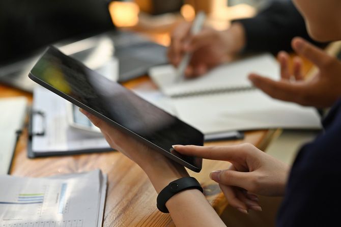 雑然とした作業机でタブレットとラップトップを広げ二人で働くオフィスワーカー