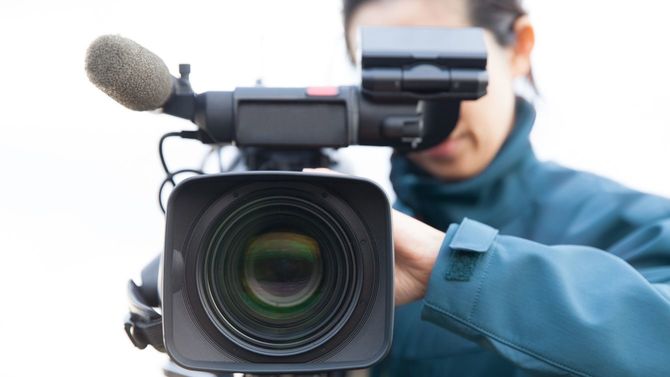 女性カメラマンがテレビカメラを構える