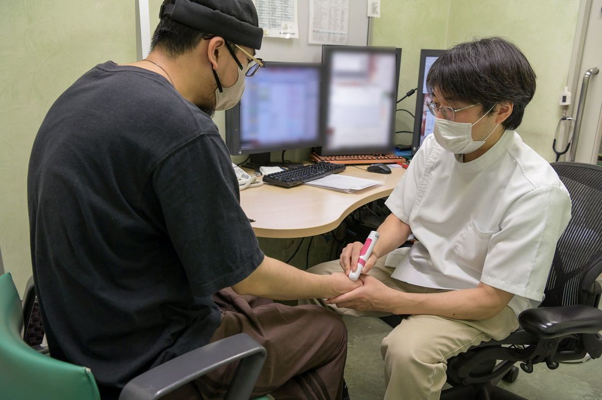 患者の手を指圧する平畑医師