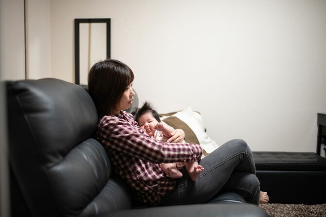 ソファで赤ん坊を抱きながら放心している母親