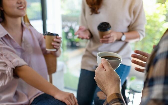 コーヒーを手に話す若者のグループ