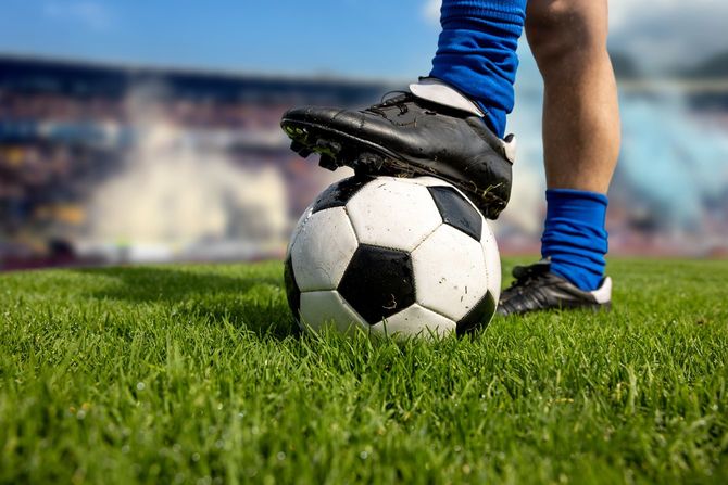 フィールドでボールを踏むフットボール選手のクローズアップ