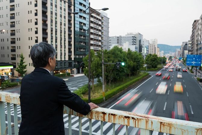 歩道橋から遠くを眺めるシニアビジネスマン