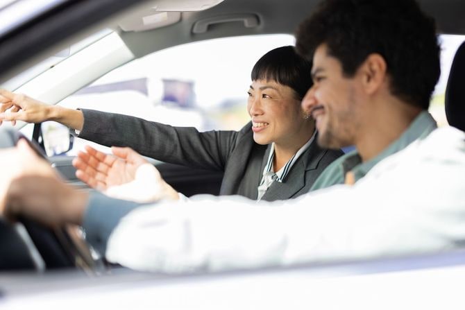 女性の自動車代理店と一緒に運転して新車を試す中東の男性