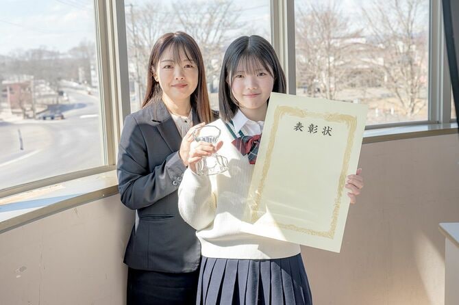 表彰状とトロフィーを持った女子高校生と教師