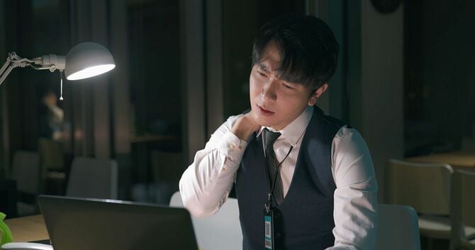 デスクワークで肩こりに悩む男性