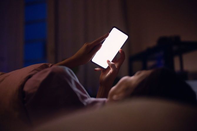 夜、ベッドでスマートフォンを使う人