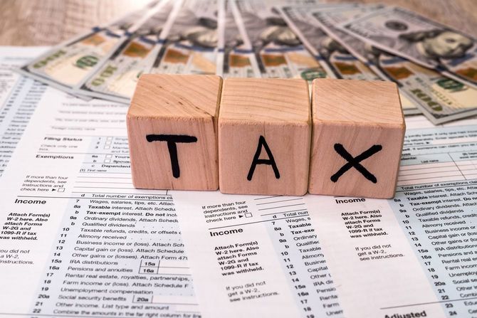 TAXと書かれた木製のキューブと100ドル札