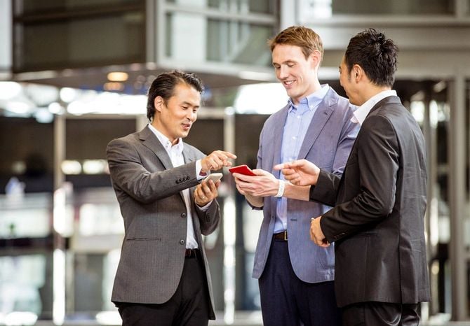 スマートフォンを持って会話する楽しそうな幹部社員たち