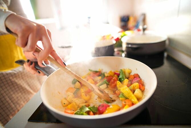 フライパンで野菜を調理する女性