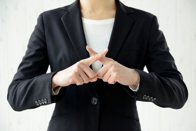 指でバツ印を作るビジネスパーソン