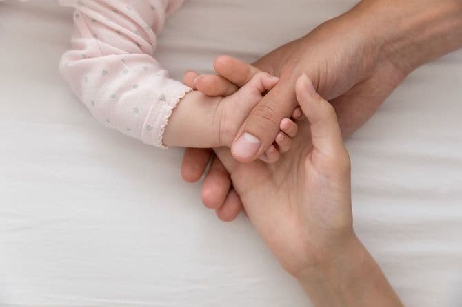 赤ちゃんの手のひらに触れるお母さん