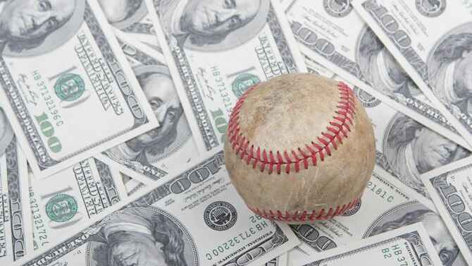 100ドル紙幣が敷き詰められた上にある野球ボール