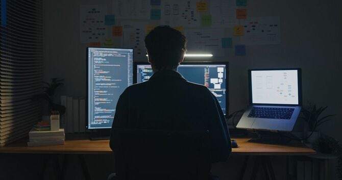 暗いオフィスで作業をするITエンジニア