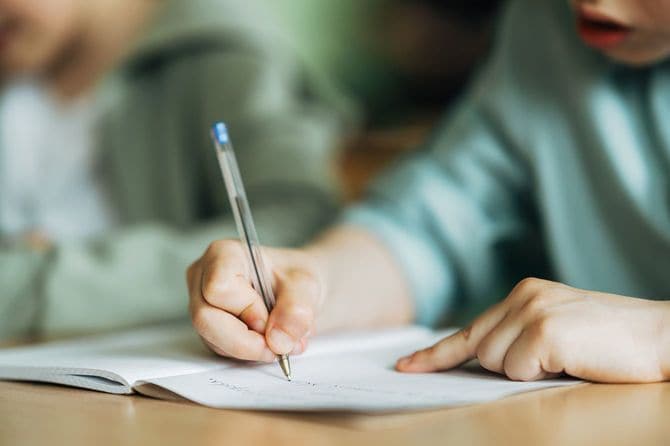 ワークブックにペンで書く少年のクローズアップ