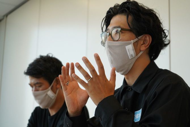 マスクを着けて話す茂木康之氏と奥に座る茂木貴史氏