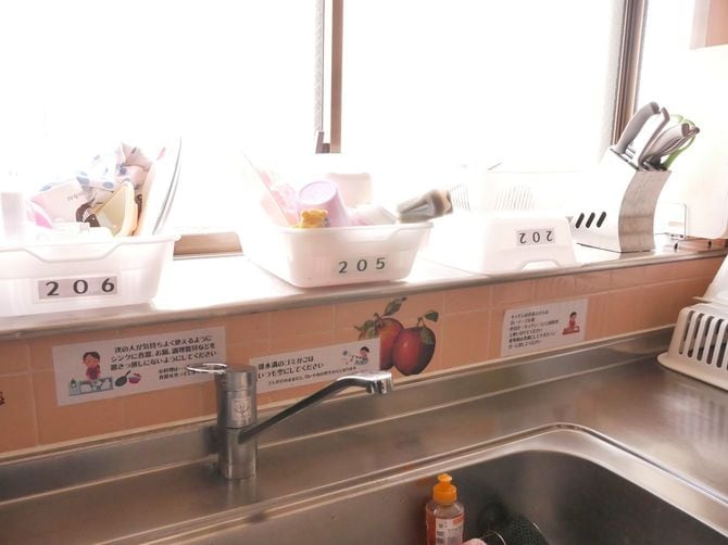 共用キッチンでは家庭ごとに調味料や食品を置く棚やゴミ箱、水切りカゴなどがある