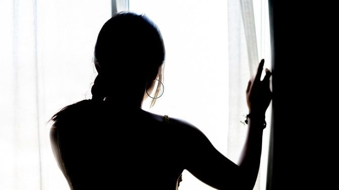 窓を開ける女性のシルエット