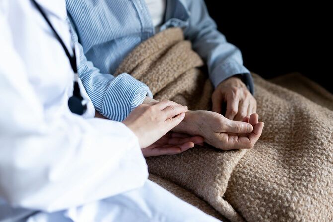 座っている高齢者の手を取り脈を測る医師