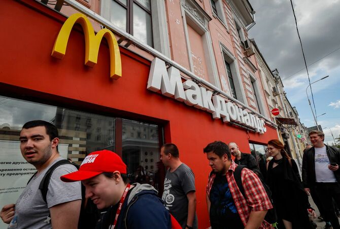 2022年6月4日、ロシア・モスクワの閉店したマクドナルドの店舗前を歩く人々。米国の世界的なファストフードフランチャイズは2022年5月16日、プレスリリースで「ロシア市場から撤退し、ロシア事業を売却する手続きを開始した」と発表した。