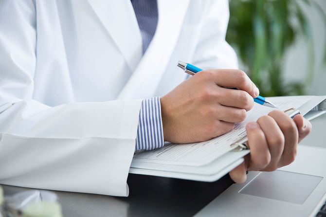 病院にて、医者が医療記録を書き込んでいる