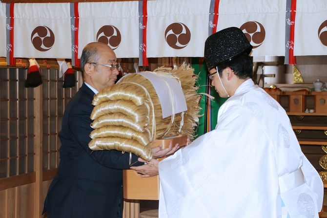 椿大神社(つばきおおかみやしろ)の権禰宜(ごんねぎ)に大麻の繊維「精麻(せいま)」を手渡す伊勢麻振興協会理事の新田均皇学館大教授(左)
