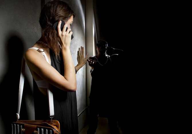 路地で助けを求めようとスマホを耳に当てる女性と追い詰める人の影