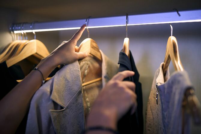 クローゼットから今日着ていく服を取り出す女性の手元