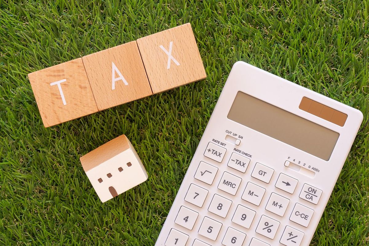 税金;コンセプトの「TAX」テキスト、家のおもちゃ、電卓を持つ3つの木製ブロック。