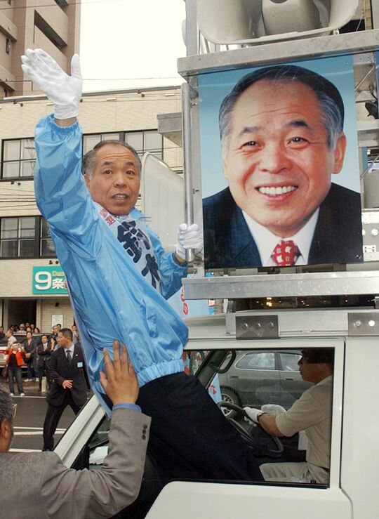 車の窓から身を乗り出して手を振る前衆議院議員の鈴木宗男氏（＝2004年6月24日、札幌市）