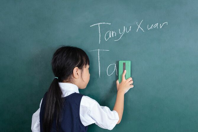教室で緑の黒板を拭くアジアの中国の小さな女の子