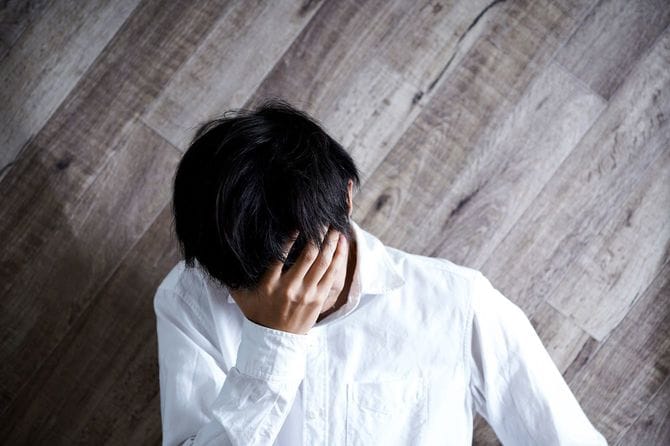 困って頭を抱える男性