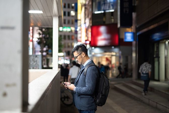 夜の街でスマートフォンを見るビジネスマン