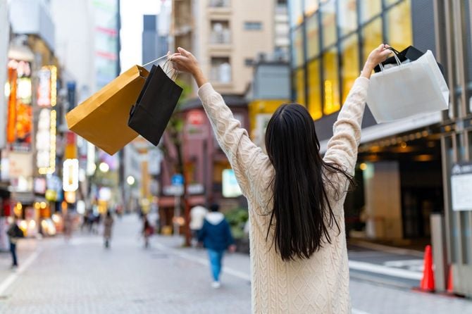 複数のショッパーを手にごきげんで渋谷の街を歩く女性