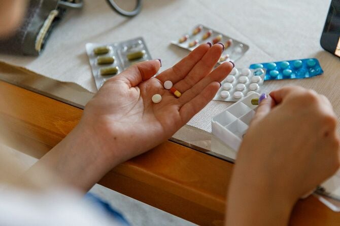 手のひらに薬と薬を握る若い女性