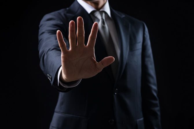 ストップの手振りをするスーツの男性