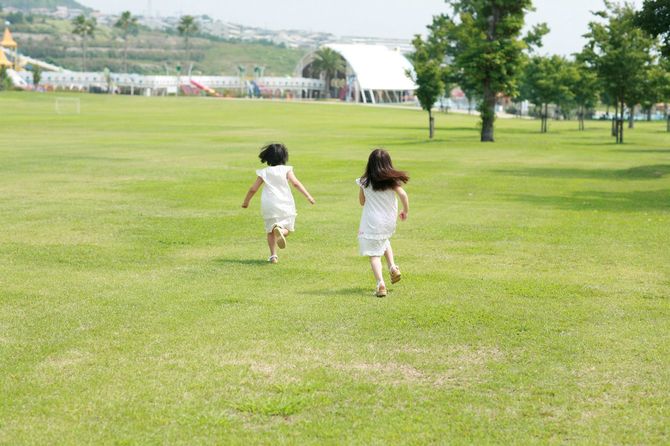 公園の野原を駆け回る二人の女の子